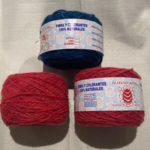 3 Skeins of Yarn. 2 skeins of red/pink and 1 skein dark blue.